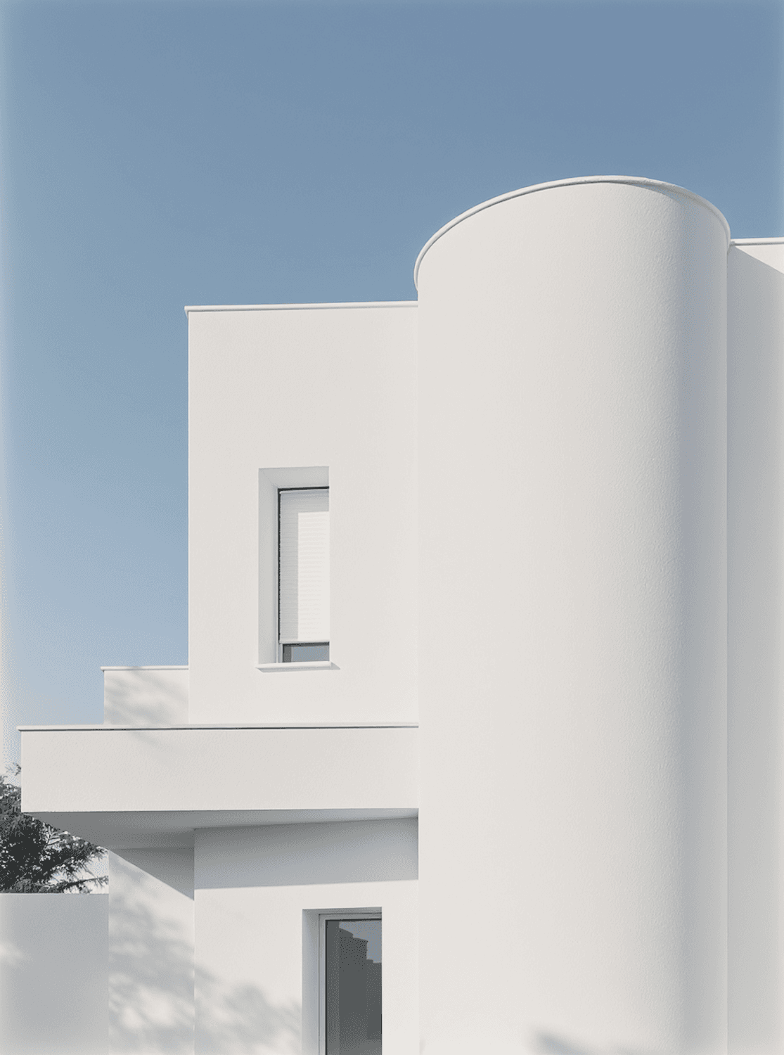 Minimal white building with geometric curves against a clear blue sky